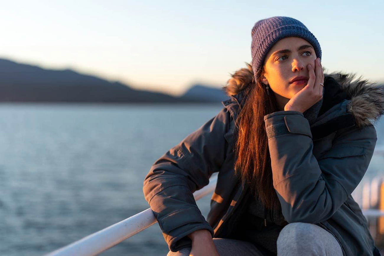 Margaret Qualley como Alex, de gorro, em uma balsa na minissérie Maid