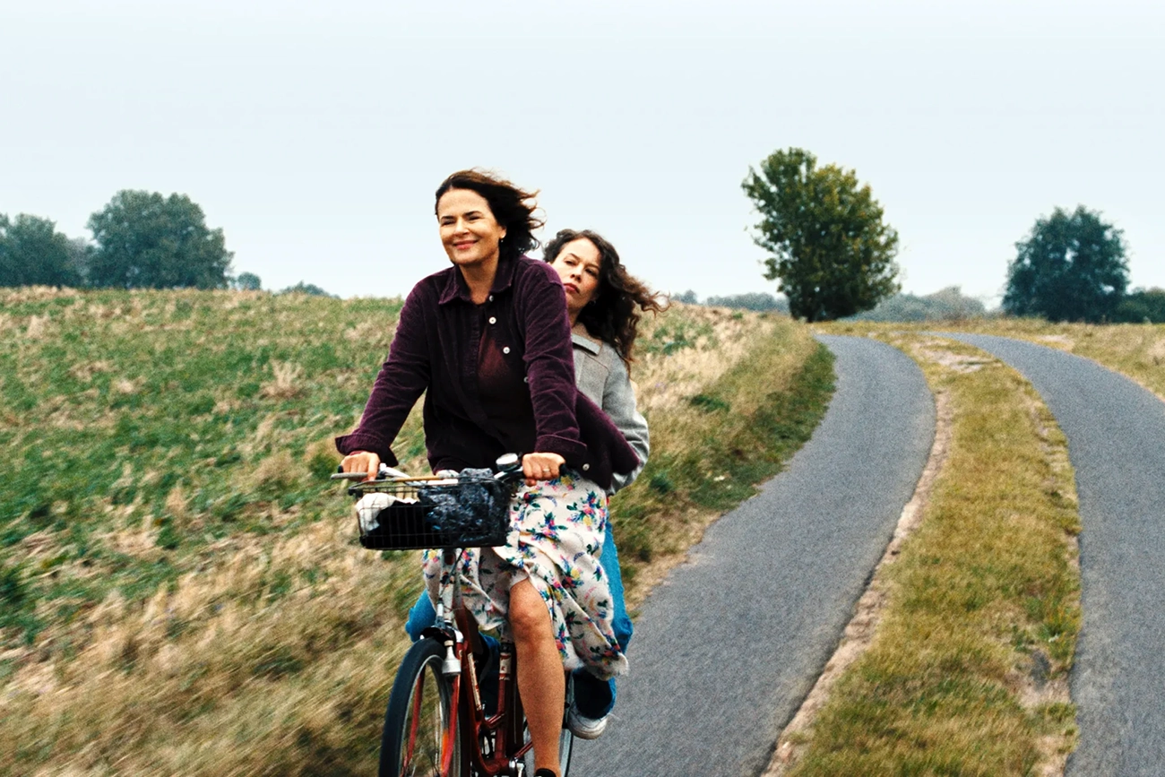 Duas mulheres compartilham uma bicicleta em uma estrada rural em Mirrors No. 3.