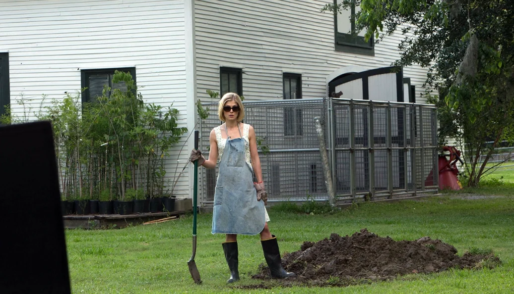 Rosamund Pike segura uma pá no jardim em cena de Sede de Vingança.