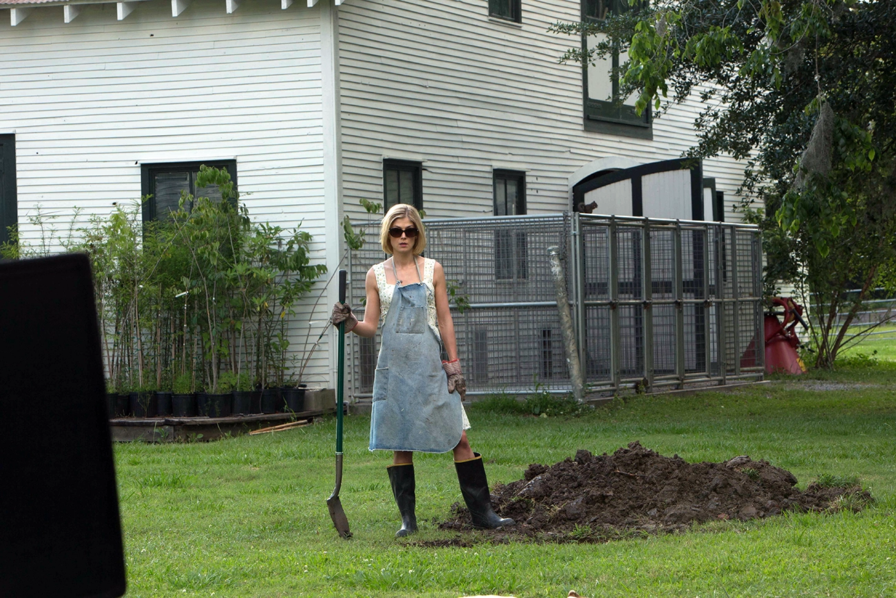 Rosamund Pike segura uma pá no jardim em cena de Sede de Vingança.