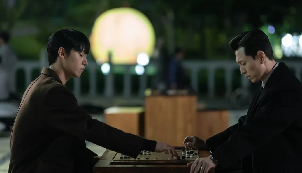 Dois homens jogam go à noite em cena de A Lição.
